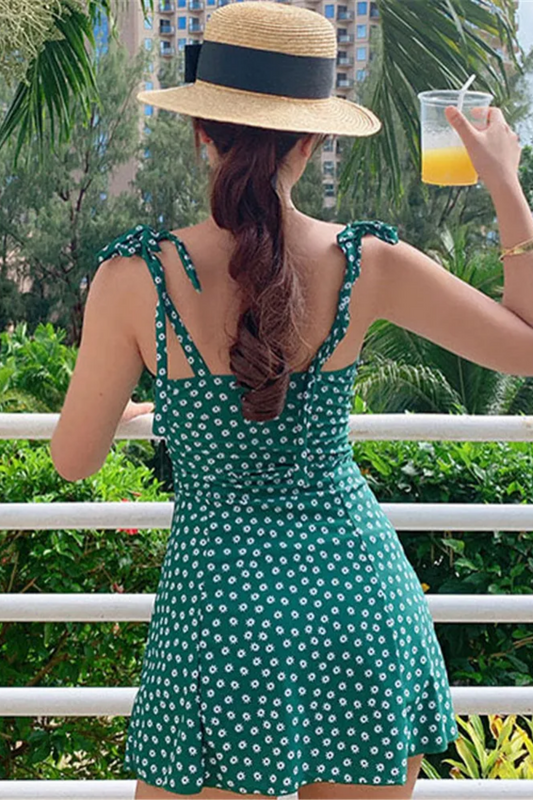 Une femme portant un "Maillot de Bain Vert Femme | 1 pièce Robe Modèle #Summer" et un chapeau de paille profite d'une journée ensoleillée avec le confort et la praticité de sa tenue, tenant une boisson rafraîchissante dans son BREEZEBEEZ.