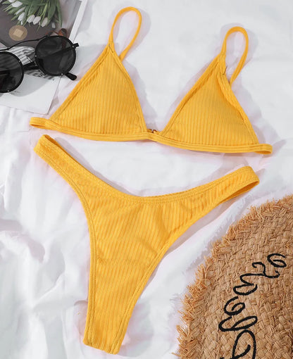 Un ensemble Maillot de Bain Femme 2 Pièces Bikini 2024 Sexy jaune vif à la texture côtelée, disposé à plat sur une surface blanche, accompagné d'accessoires d'été dont des lunettes de soleil et un chapeau de paille. Ce très bel ensemble est parfait pour vos vacances par BREEZE BEEZ.