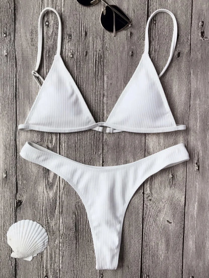 Un maillot de bain sexy BREEZE BEEZ Maillot de Bain Femme 2 Pièces Bikini 2024 blanc disposé sur une surface en bois avec une paire de lunettes de soleil et un coquillage, évoquant une ambiance prête pour la plage.