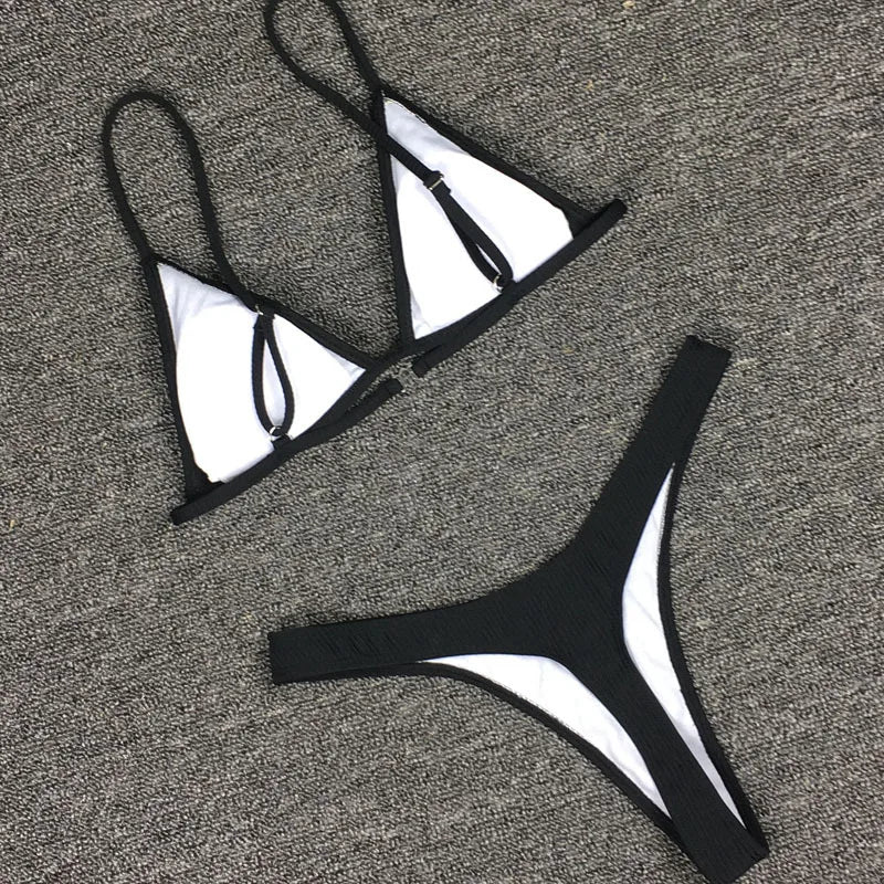 Un ensemble de Maillot de Bain 2 Pièces Noir Bikini 2024 Sexy disposé soigneusement sur une surface tapissée de gris. Plongez dans un monde où style et confort se rencontrent : l'oasis des femmes.