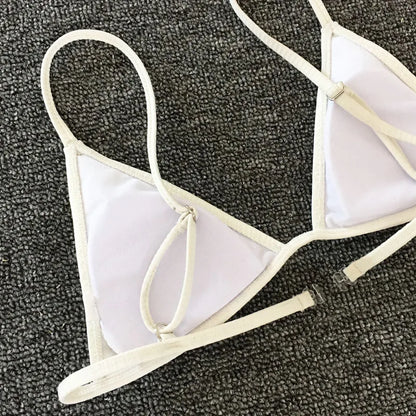 Un haut de bikini triangulaire BREEZE BEEZ blanc posé sur une surface texturée en sable.