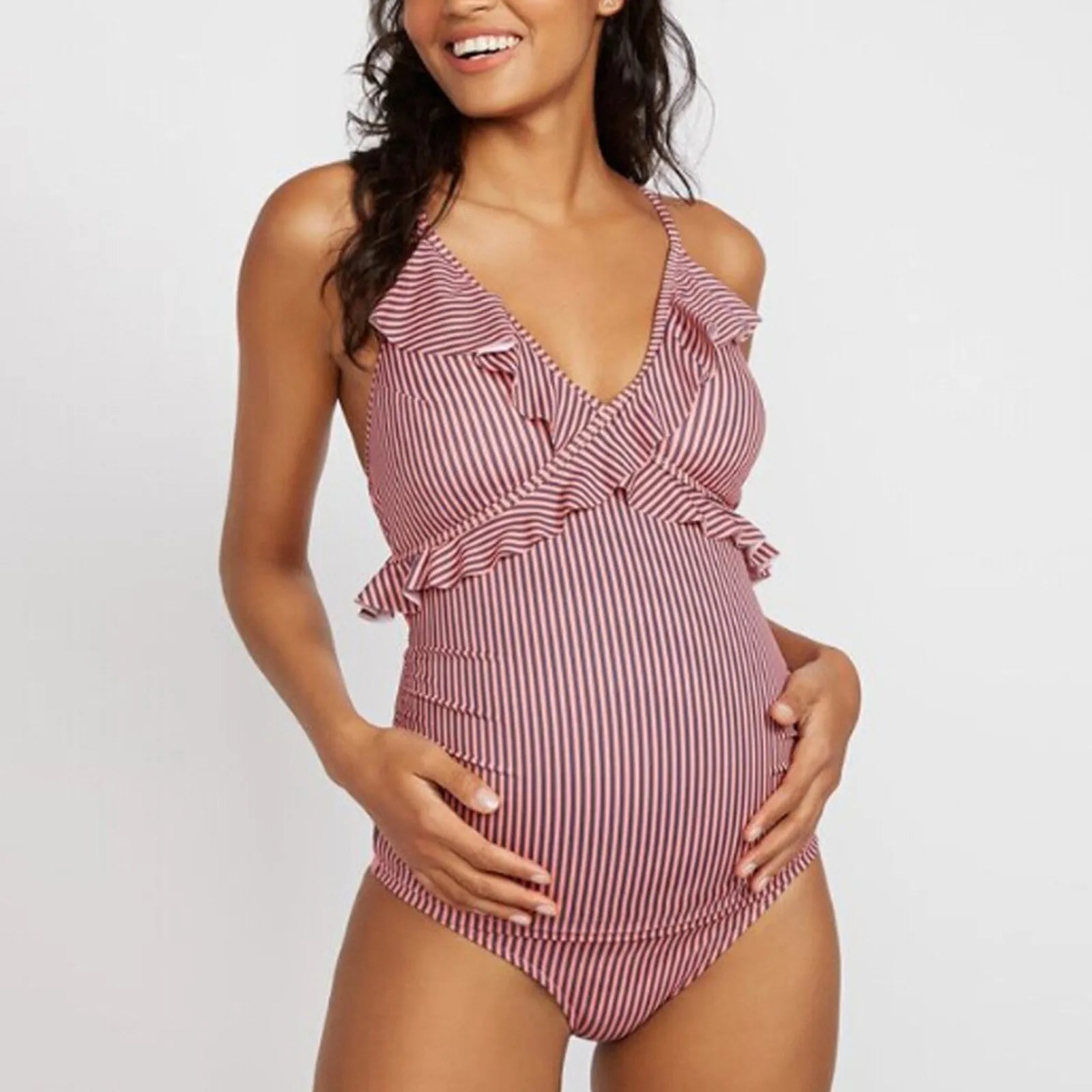 Une femme portant un Maillot de Bain Femme Enceinte 1 Pièce rayé de BREEZE BEEZ avec des détails de volants, conçu pour le confort pendant la Maternité.