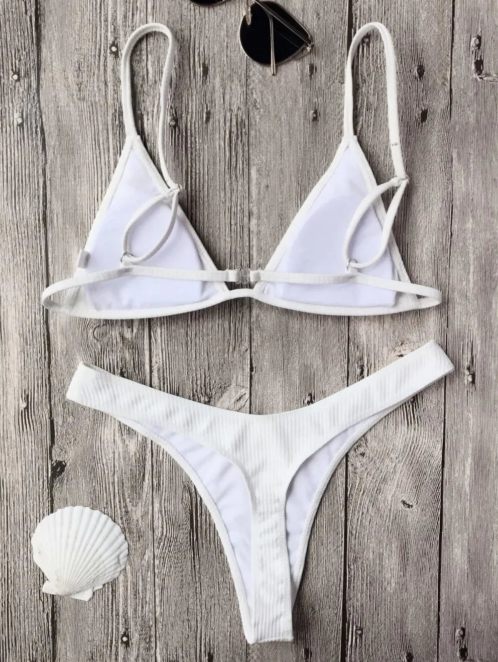 A Maillot de Bain Femme 2 Pièces Bikini 2024 Ensemble de maillots de bain sexy de BREEZE BEEZ soigneusement disposés sur un fond en bois rustique, accompagné d'un coquillage et d'une paire de lunettes de soleil, évoquant une ambiance balnéaire sereine.