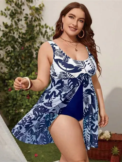 Une femme à imprimé tropical bleu et blanc BREEZEBEEZ Maillot de Bain Femme Grande Taille | Forte Poitrine Bleu pose avec assurance en extérieur, affichant un style estival ludique, alliant confort et style.