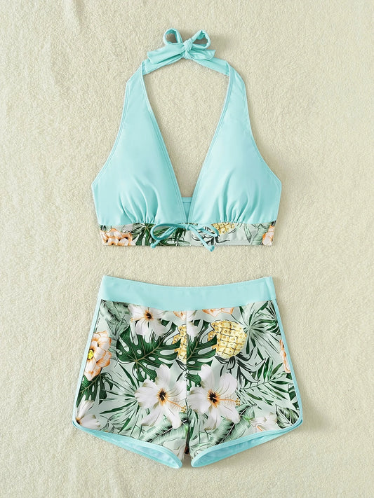 Un haut de bikini BREEZE BEEZ élégant à col licou bleu clair associé à un short de bain taille haute à imprimé floral assorti, sur un fond neutre et doux. Parfait pour un look balnéaire chic.