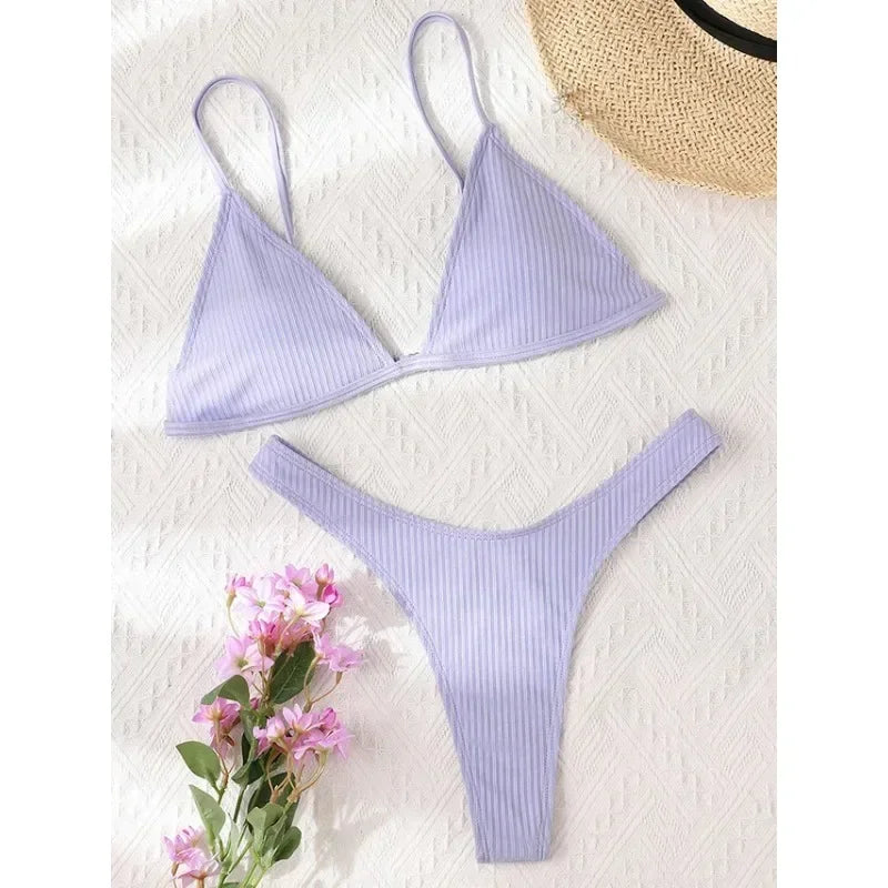 Un Maillot de Bain Femme 2 Pièces Bikini 2024 Sexy de BREEZE BEEZ soigneusement présenté sur un fond blanc texturé, accompagné d'un chapeau de paille et d'un petit bouquet de fleurs roses, évoquant un sentiment d'été et de fête.