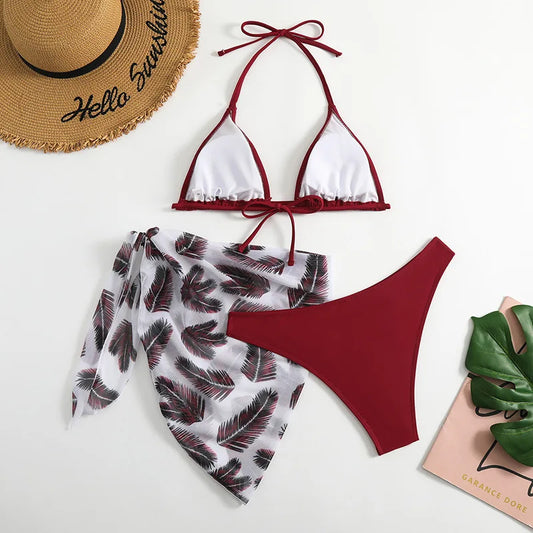 Prêt pour l'été : un BREEZE BEEZ chic blanc et rouge Maillot de Bain Femme 3 Pièces | Ensemble haut & Bas associé à un paréo à imprimé tropical, complété par un élégant chapeau de paille et des sandales vertes, le tout prêt pour une journée confortable et tendance à la plage.