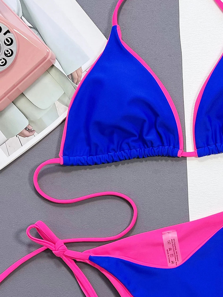 Un Bikini Maillot de Bain 2 Pièces Bleu vibrant bleu et rose de la marque BREEZE BEEZ disposé sur un fond bicolore avec un téléphone rétro et quelques papiers dans le coin, Bienvenue dans notre boutique en ligne.