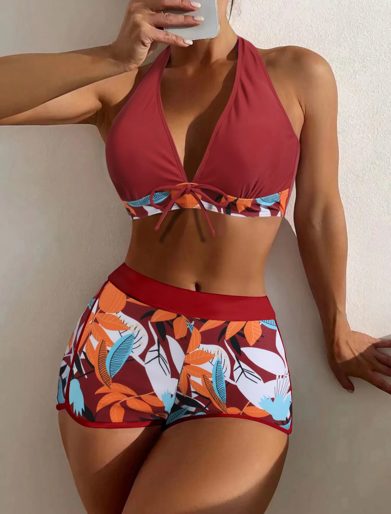 Une personne portant un Maillot de Bain Boxer Femme 2 pièces haut de bikini sexy et un short à imprimé tropical posant pour une photo sur le sable.