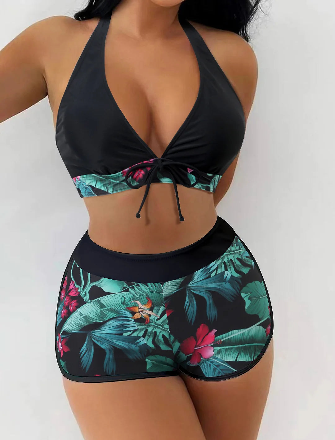 Une femme pose dans un BREEZE BEEZ Maillot de Bain Short Boxer 2 pièces confortable et confortable sur le thème tropical avec un haut dos nu à col haut et un bas taille haute.