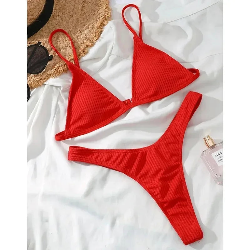 Maillot de Bain Rouge 2 Pièces Bikini 2024 Sexy de BREEZE BEEZ disposé sur une surface blanche, avec des accessoires à proximité suggérant une journée de plage ensoleillée à venir pour profiter des vacances.