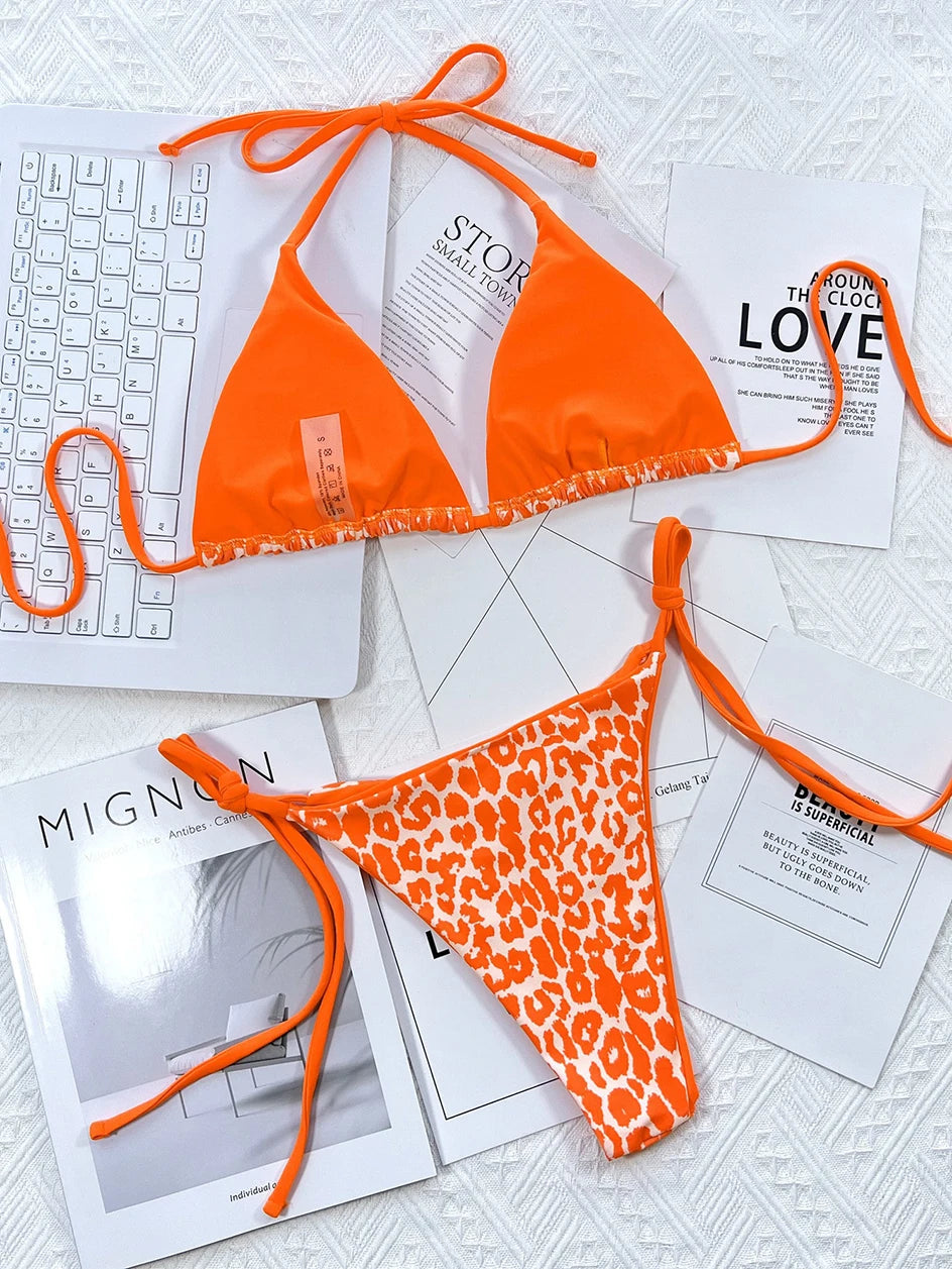 Un bikini Maillot de Bain Femme 2 Pièces vibrant avec des caractéristiques à nouer et un motif imprimé léopard sur le bas, affiché au-dessus des magazines de mode et à côté d'un clavier blanc, créant une atmosphère balnéaire chic et élégante par BREEZE BEEZ.