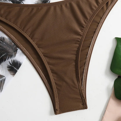 Une vue rapprochée d'un très beau Maillot de Bain Femme 3 Pièces | Ensemble haut & Bas BREEZE BEEZ marron posé à plat, avec du feuillage tropical et une touche de tissu rose en arrière-plan.