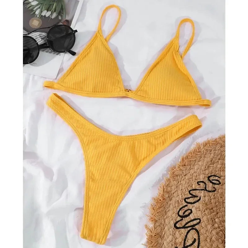 Ensemble de bikini BREEZE BEEZ jaune soleil soigneusement disposé aux côtés d'accessoires d'été, prêt pour une journée de plage très belle et confortable pendant les vacances.