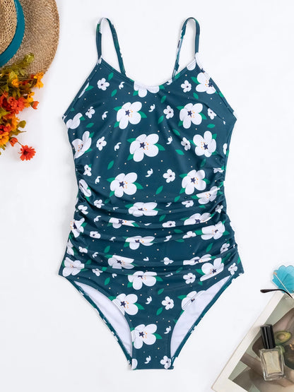 Un très beau BREEZE BEEZ Maillot de Bain Vert Femme 1 Pièce à motif floral disposé sur un fond blanc, entouré d'accessoires d'été dont un chapeau de paille, des fleurs colorées, une paire de lunettes de soleil et du vernis à ongles.