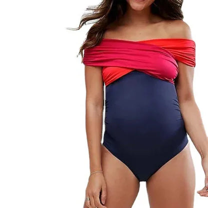 Une femme portant un confortable Maillot de Bain Femme Enceinte bicolore BREEZEBEEZ avec un haut sans bretelles rouge qui passe au bleu marine en bas.