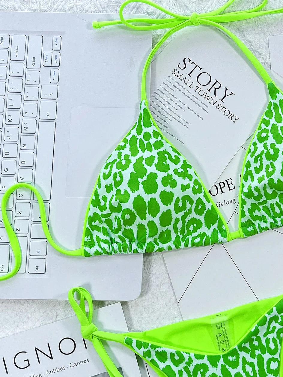 Un haut de bikini Maillot de Bain Vert Clair 2 Pièces vibrant de BREEZE BEEZ posé sur un magazine de mode ouvert à côté d'un clavier d'ordinateur portable blanc, symbolisant un mélange de travail, de loisirs et de planification de très belles vacances.