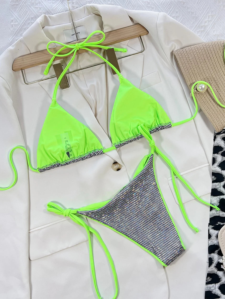 Un Maillot de Bain Femme 2 Pièces vert vif unique avec des détails à nouer disposés sur un fond en tissu de couleur crème par BREEZE BEEZ.