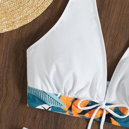 Un Maillot de Bain Short Femme 2 pièces Sexy blanc avec une bande à motifs bleue et orange placée sur une surface en bois à côté d'un chapeau de paille, suggérant un thème d'été et de plage par BREEZE BEEZ.