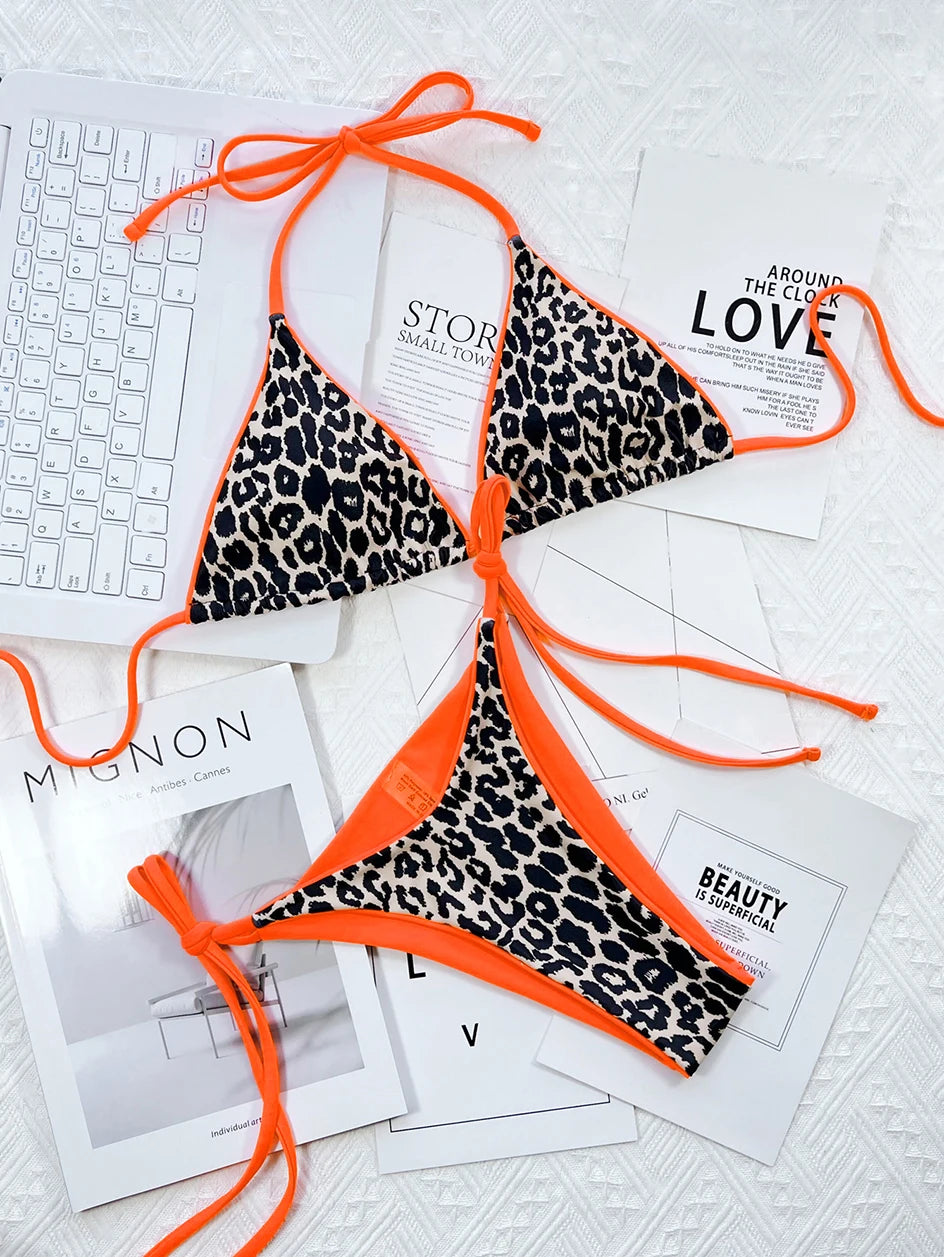 Un Maillot de Bain Femme 2 Pièces Bikini à imprimé orange vif et léopard de BREEZE BEEZ disposé artistiquement sur une sélection de magazines élégants en noir et blanc, créant un contraste saisissant qui parle d'un mélange de motifs sauvages et de littérature chic, parfait pour un.