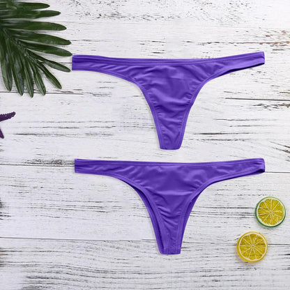 Deux BREEZE BEEZ Bas Maillot de Bain Femme 1 Pièce Violet sont exposés sur une surface en bois blanc, accompagnés d'une feuille tropicale verte et de tranches de citron vert, suggérant un thème d'été ou de plage. Bienvenue dans notre boutique en ligne, l'oasis