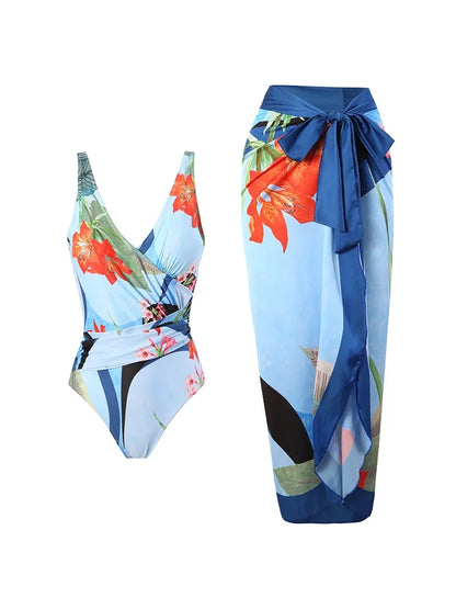 Un élégant ensemble Maillot de Bain Bleu 2 Pièces de BREEZE BEEZ comprenant un maillot de bain une pièce à imprimé floral associé à une jupe portefeuille assortie, affichant un design tropical vibrant avec des teintes bleues et des fleurs rouges, parfait pour une escapade à la plage.