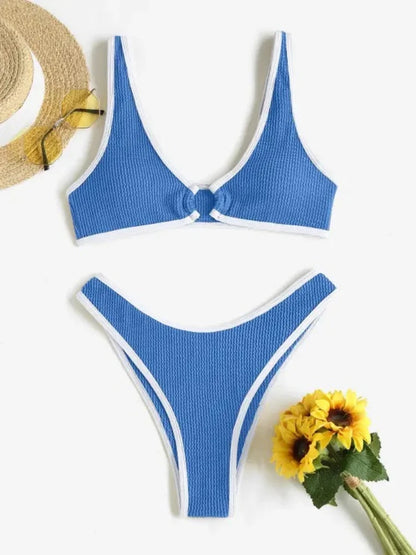 Ambiance estivale : un ensemble Maillot de Bain 2 Pièces Bleu composé d'un haut noué sur le devant et d'une culotte échancrée, conçu pour toutes les morphologies, associé à un chapeau de paille et des lunettes de soleil, accompagné d'un joyeux bouquet de fleurs jaunes de BREEZE BEEZ